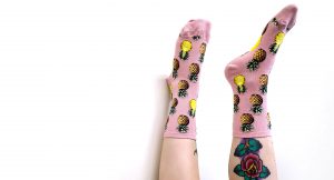 Pineapple socks in pink by ModSocks worn by woman with tattoo.