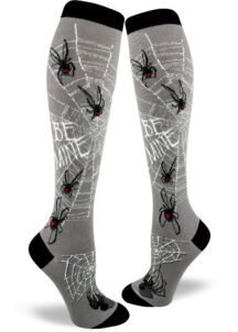 Spider socks for women with black widow spiders with red hearts on their abdomens standing on silver webs that say "BE MINE."