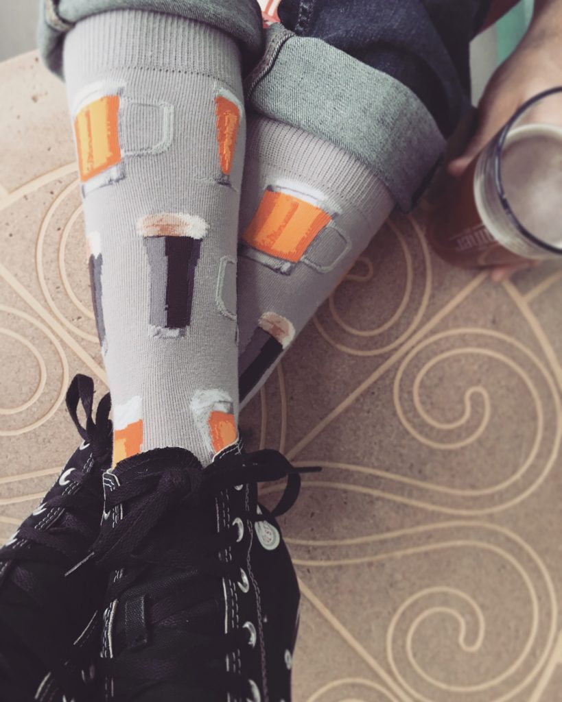Beer socks by ModSocks with craft beer at a brewery.