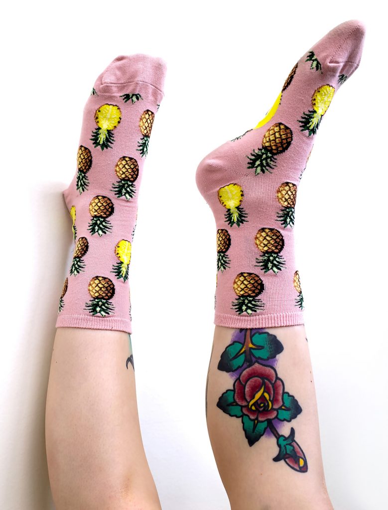 Pineapple socks in pink by ModSocks worn by woman with tattoo.