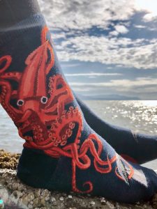 Squid socks by ModSocks with a giant squid and whale socks near the ocean.