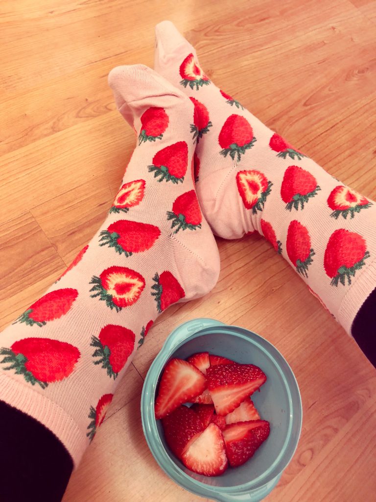 Strawberry socks are worn by a woman holding sweet strawberries.
