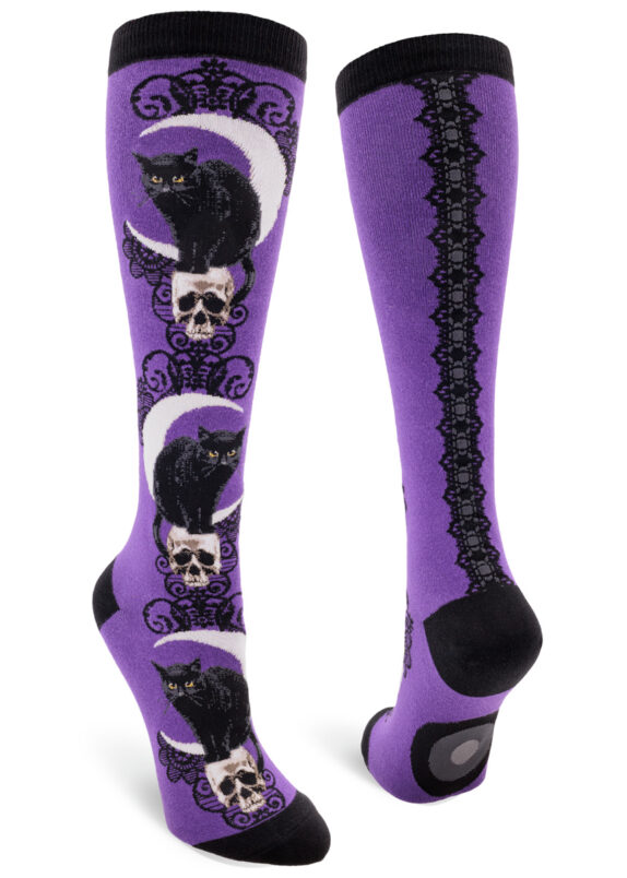 Purple knee socks with a design featuring a black cat hunched on a skull in front of a crescent moon.