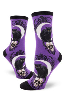 Purple women's crew socks with a design featuring a black cat hunched on a skull in front of a crescent moon.