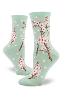 Cherry blossom crew socks with a pink floral design on a light green background.