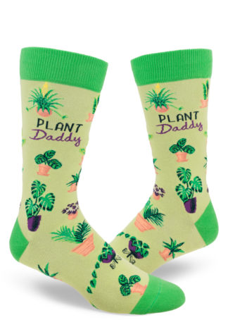 Cute men's crew socks in shades of green say "Plant Daddy" on the side with an all-over pattern of various houseplants.