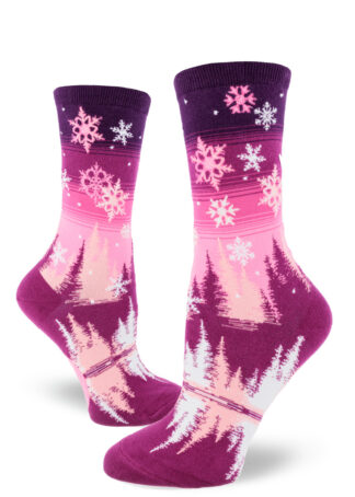 Snowflake women's crew socks depict a winter scene over a pink and purple gradient striped sky.