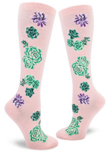 Knee socks with a design of green, purple and pink succulent plants on a pink background.